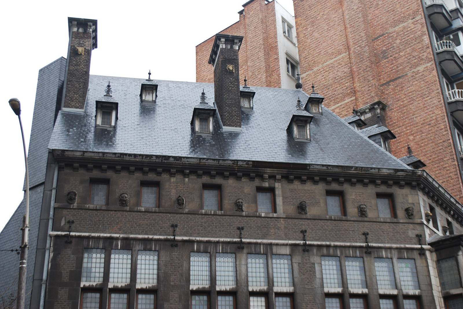 Gebouw met een leien dak, dakkapellen en hoge schoorstenen